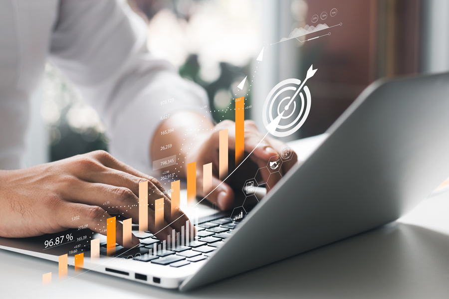 Hands calculating complex costs near a laptop and small gears, symbolizing cost precision with Syspro Landed Cost Tracking.